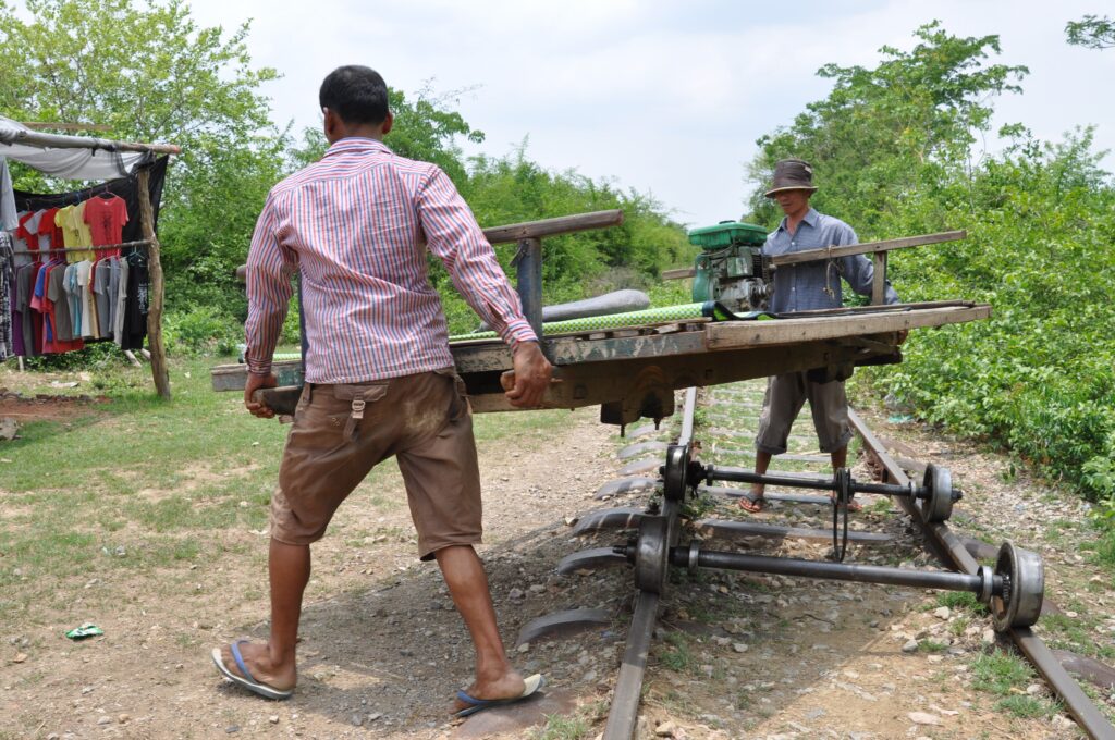 Operators lifting a bamboo train off the track to let another pass, Battambang, Cambodia