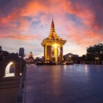 A gilded Buddhist monument in Phnom Penh under a sunset sky