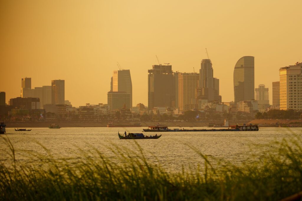 Boats on the river at sunset with the Phnom Penh skyline behind